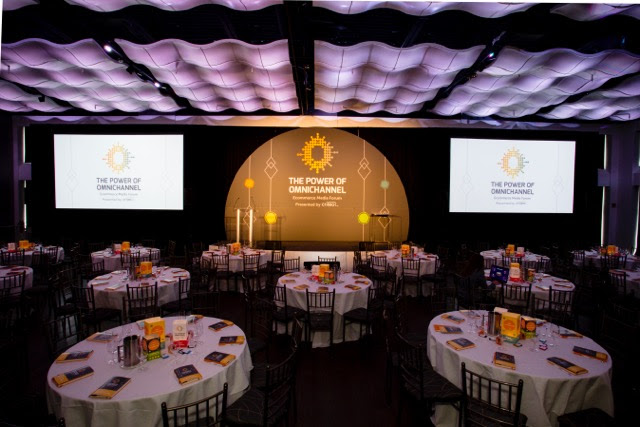 Two screens and stage in front of round tables set for a program