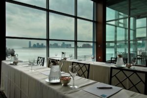 Pier Sixty in a classroom set up, note pads, pens, water service on the tables with water views in the background
