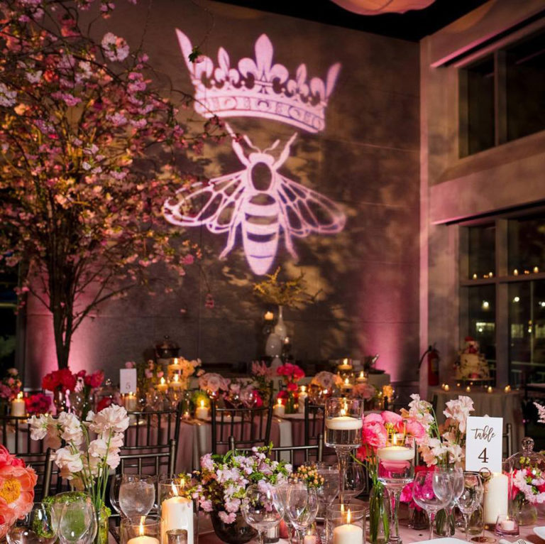 Queen bee logo projected onto wall above dinner tables