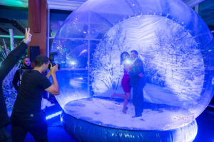 Couple having their picture taken inside giant snow globe