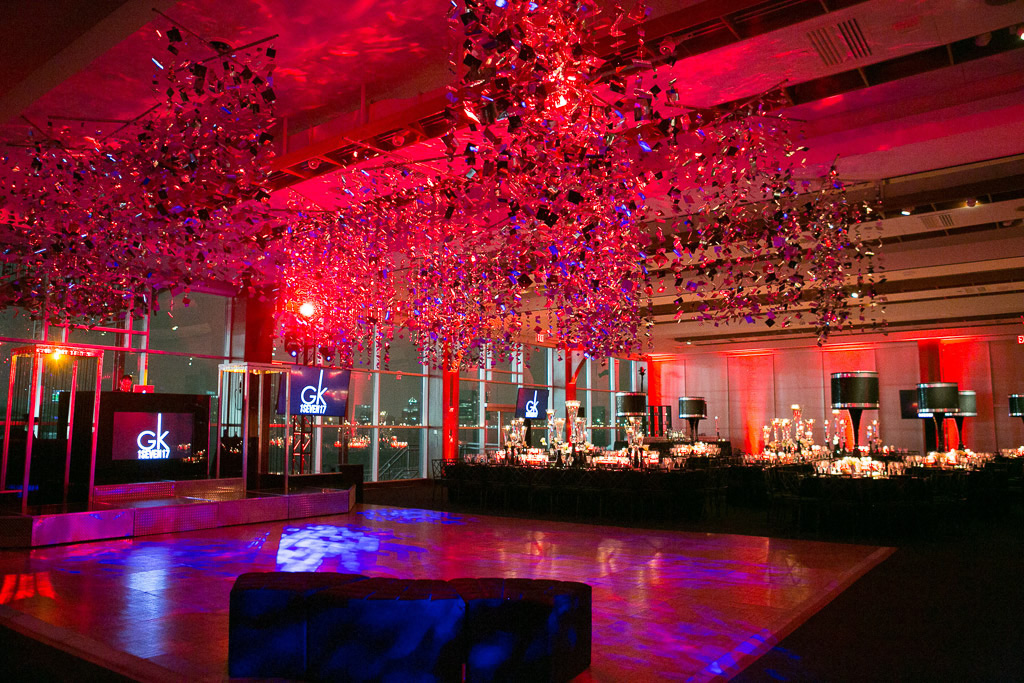 Glittery decorations hang above dance floor in red-lit venue.