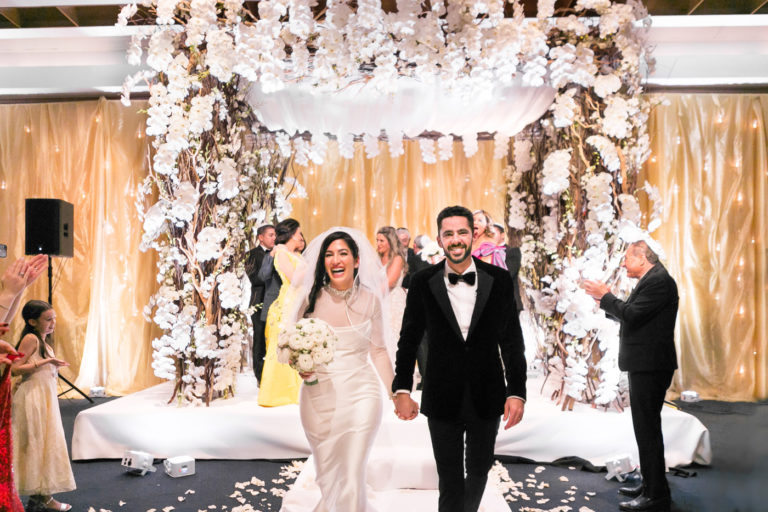 Couple smiles at camera as they walk back down aisle after wedding ceremony.