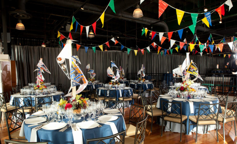 Colorful banners in air above baseball-pennant decorated dinner tables.