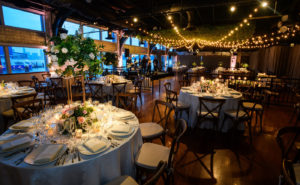 Tables set with floral centerpieces under decorative lighting