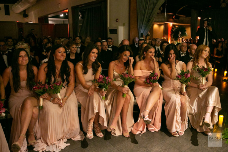 Bridesmaids on the first row wearing soft pink matching dresses