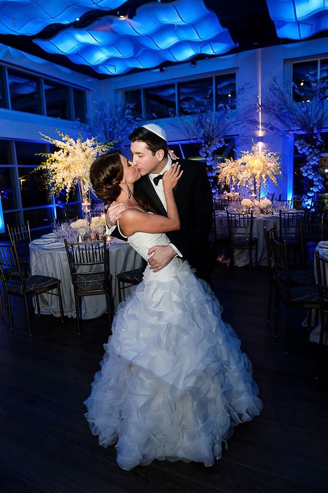 Bride and Groom kissing in the middle of the ballroom set for dinner at Current