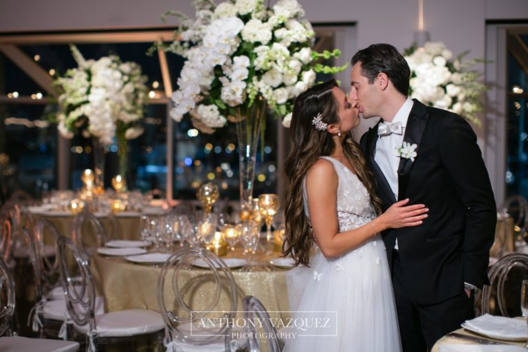 Bride and Groom kissing, tables set for dinner in the background